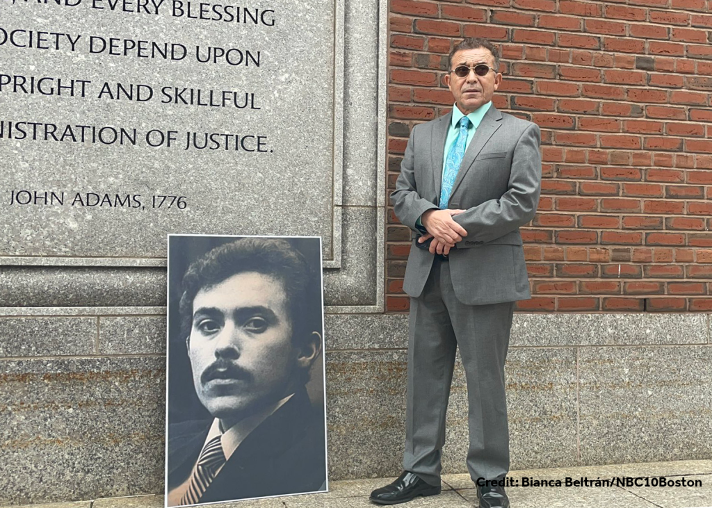 Victor Rosario stands next to a photo of himself taken when he was 24-years-old sitting in a courtroom. Credit: Bianca Beltrán/NBC10Boston